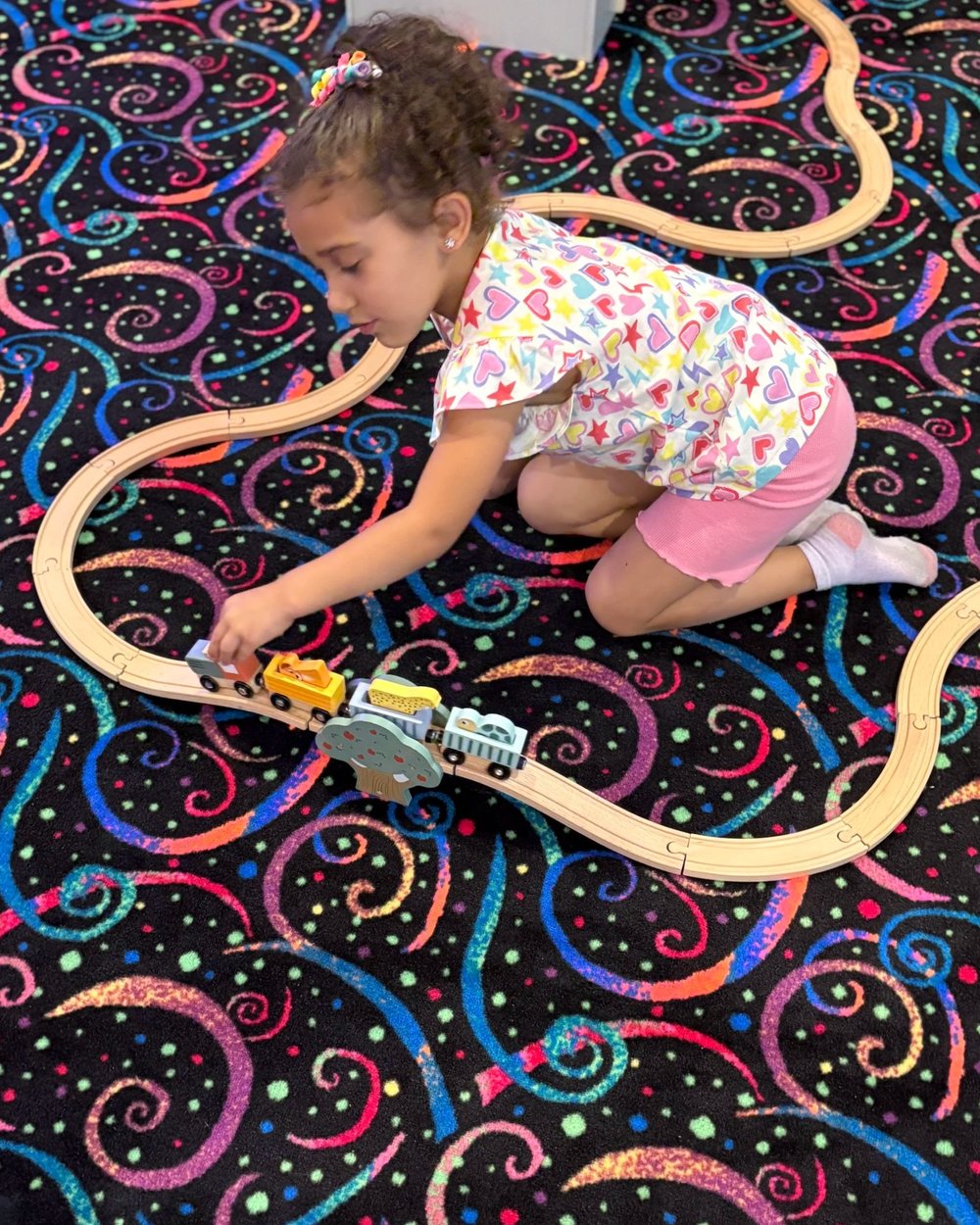 A child playing with wooden trains on a track at The Grove