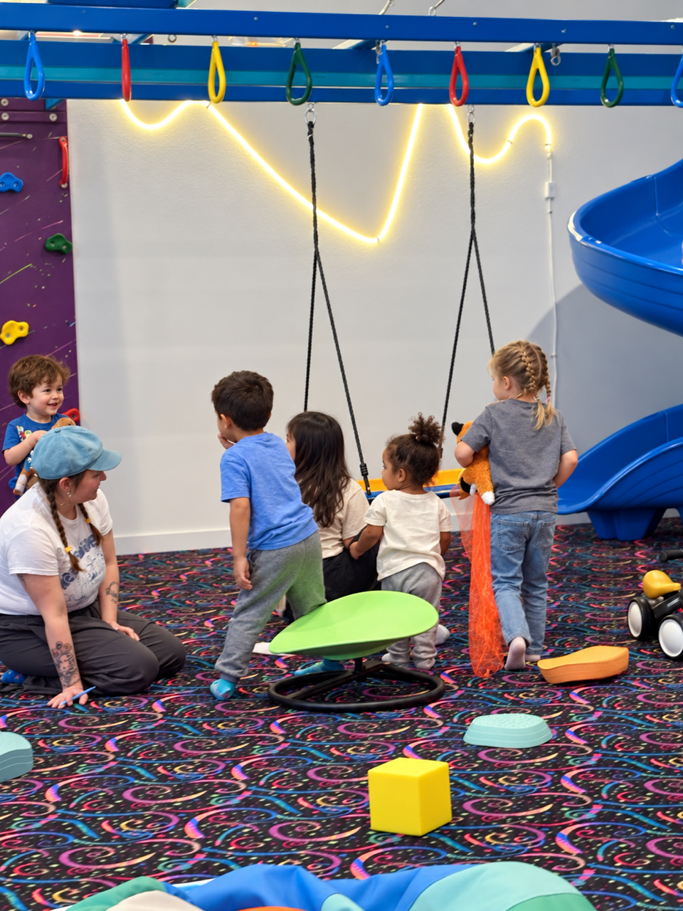 Children and a caregiver gathering around swings and play equipment at The Grove